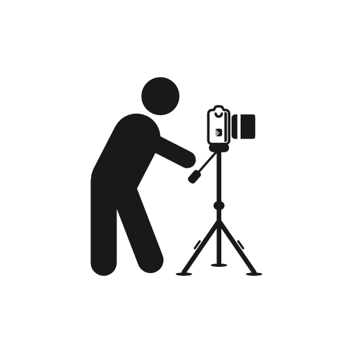 Photographer standing behind photo camera on a tripod from side view